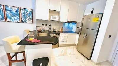 a kitchen with a refrigerator and a table with a wine glass at Cana Rock Star-Two apartments very close-Ground floor direct access to the pool in Punta Cana