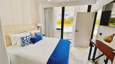 a bedroom with a bed with blue and white pillows at Cana Rock Star-Two apartments very close-Ground floor direct access to the pool in Punta Cana