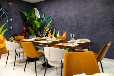 a dining room with wooden tables and yellow chairs at Habana Hotel Y Restaurante in Higuey