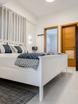 a white bedroom with a large white bed with a mirror at Goistay Elegant Refugio Caribeo 1br Gym Pool Naco in Santo Domingo