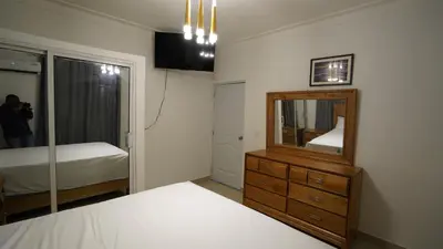 a person taking a picture of a bedroom with a mirror at Villa Sol Taino, Hotel en Boca chica, 5 minutos del Aeropuerto Internacional las Américas in La Golondrina