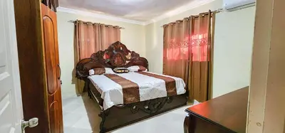 a bedroom with a bed with a wooden headboard at Villa lujosa con piscina bayaguana in Bayaguana
