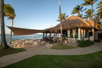 a restaurant on the beach with chairs and palm trees at Velero Beach Resort in Cabarete