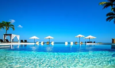 a swimming pool with chairs and umbrellas on the beach at Velero Beach Resort in Cabarete