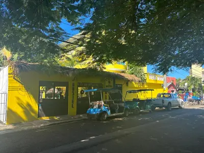 a small golf cart parked in front of a yellow building at Coco Hotel and Hostel in Sosúa