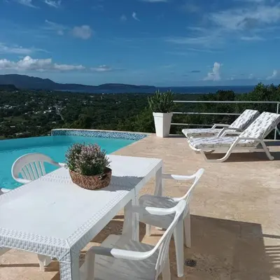 a white table and chairs next to a swimming pool at Apartamento panorámico vista al mar in Las Galeras