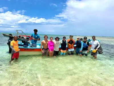 a group of people standing in the water next to a boat at Beach Terrace Loft in Buen Hombre in Buen Hombre