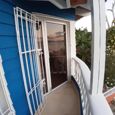 a blue house with a balcony with a glass door at BLUE HOUSE OCEAN VIEW in Santa Bárbara de Samaná