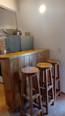 a kitchen with three wooden stools at a counter at Doña Mayra Aparta Hotel, Rustico in Las Terrenas
