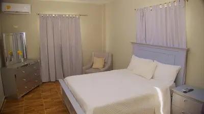 a bedroom with a white bed and a dresser with a mirror at Hotel Vista al Morro in San Fernando de Monte Cristi
