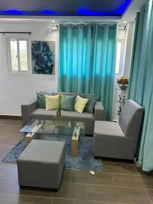 a living room with blue curtains and a couch at JC Caribe Aparta Hotel #1 in La Caleta
