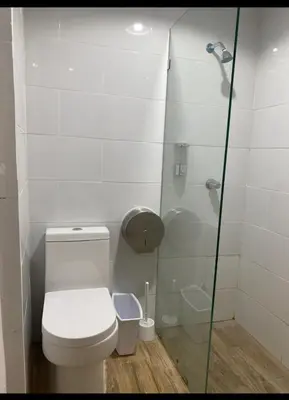 a bathroom with a toilet and a glass shower at Estudio privado con vigilancia 24/7 con entrada independiente, in Santiago de los Caballeros
