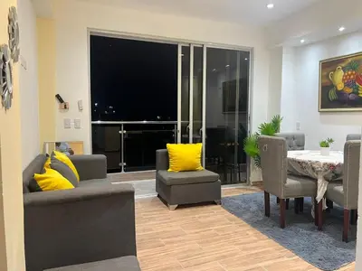 a living room with a table and yellow pillows at HABITACIONES CON VISTA a LA BAHIA LA FAMILIA in Santa Bárbara de Samaná