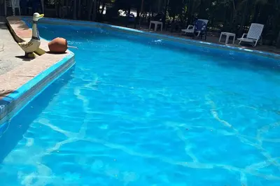 a swimming pool with blue water and chairs in it at Apartamento pisó 1 parqueo, piscina, terraza y más in Azua de Compostela