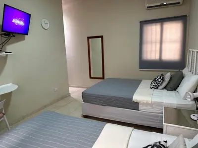 a bedroom with two beds and a flat screen tv at Hotel Plaza Kavia in Santo Domingo