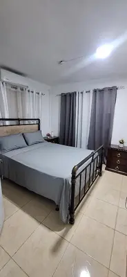 a bedroom with a bed with blue sheets and curtains at Casa en Villa Marchena azua in Azua de Compostela