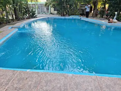 a large blue swimming pool with a person standing in it at Habitación doble Villa Marchena Azua in Azua de Compostela