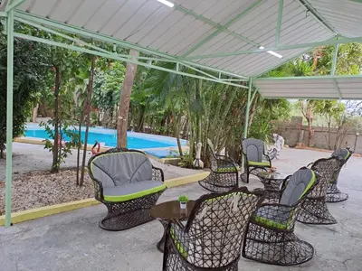 a group of chairs and tables under a canopy near a pool at Habitación doble Villa Marchena Azua in Azua de Compostela