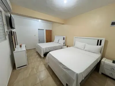 a hotel room with two beds and a television at Habitación doble Villa Marchena Azua in Azua de Compostela