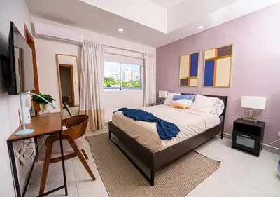 a bedroom with a bed and a desk and a window at Refa 304 in Santo Domingo