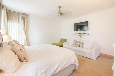 a white bedroom with a bed and a chair at 3BR apartment with beach access and ocean view in Juan Dolio