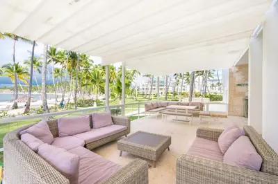 an outdoor living room with couches and palm trees at 3BR apartment with beach access and ocean view in Juan Dolio