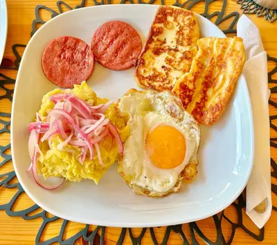 a plate of breakfast food with an egg and toast at La Curadiña - Encuentro Surf Resort in Cabarete
