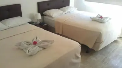 two beds with white sheets with flowers on them at Hotel Tropicana Santo Domingo in La Viva