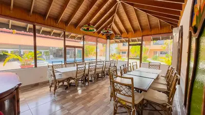 a dining room with tables and chairs and windows at Hotel Tropicana Santo Domingo in La Viva