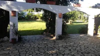 a stone patio with an archway in a yard at Hotel Tropicana Santo Domingo in La Viva