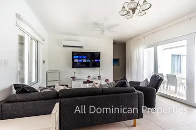 a living room with a couch and a tv at Sosua Ocean Village, Villas Nuevas con piscinas privadas! in Sosúa