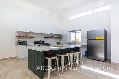 a kitchen with a green island and a refrigerator at Sosua Ocean Village, Villas Nuevas con piscinas privadas! in Sosúa