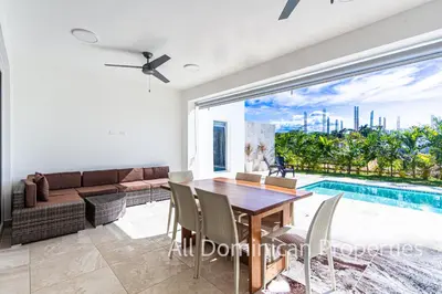 a dining room with a table and a pool at Sosua Ocean Village, Villas Nuevas con piscinas privadas! in Sosúa