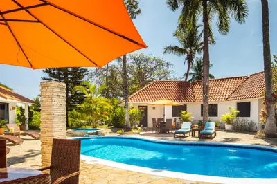 a house with a swimming pool and an orange umbrella at Garden By The Sea in Sosúa