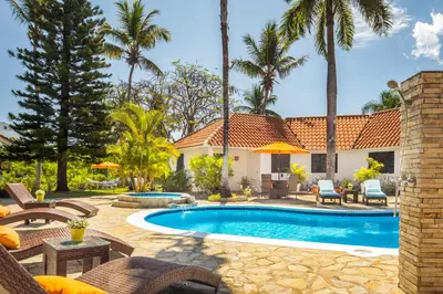 a backyard with a swimming pool and palm trees at Garden By The Sea in Sosúa