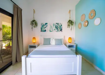 a bedroom with a white bed and two lamps at Garden By The Sea in Sosúa