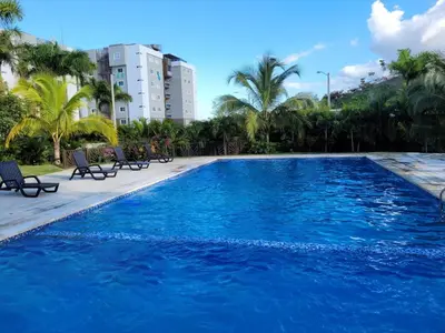 a large blue swimming pool with chairs and palm trees at El mejor alojamiento en Santiago in Santiago de los Caballeros