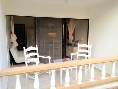 a balcony with two white chairs and a couch at Cita del Sol City Apartments in Cabarete