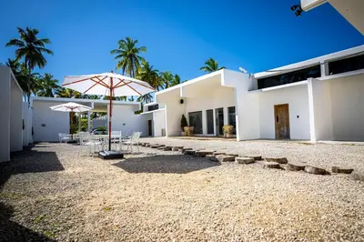 a large white building with an umbrella and chairs at The Palm Bay Club Lodge in Nagua