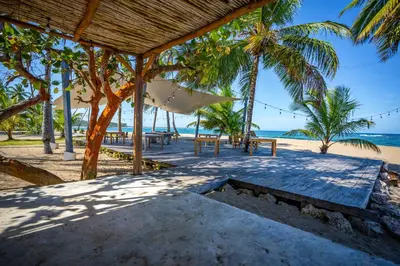 a picnic table on the beach with palm trees at The Palm Bay Club Lodge in Nagua
