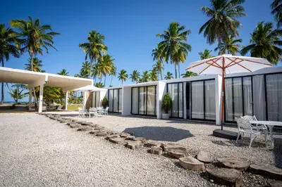 a building with an umbrella and chairs and palm trees at The Palm Bay Club Lodge in Nagua
