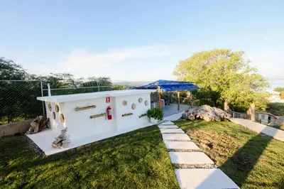 a small white house with a green yard at Hotel Don Bululo Camping Lodge in Punta Rucia
