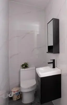 a white bathroom with a toilet and a sink at Oasis en la Sultana del Este in San Pedro de Macorís