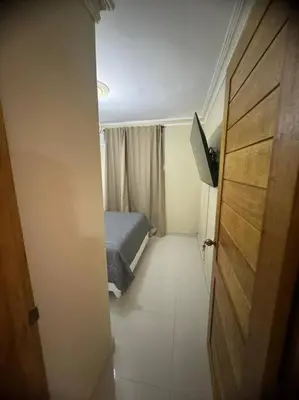 a small bedroom with a bed and a door at Oasis en la Sultana del Este in San Pedro de Macorís