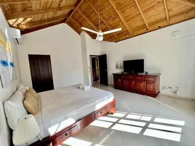 a bedroom with a large bed and a television at Casati Pearl House, Big House With Private Pool in Bombita