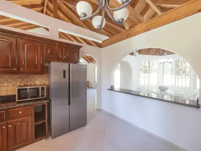 a kitchen with wooden cabinets and a stainless steel refrigerator at Casati Pearl House, Big House With Private Pool in Bombita