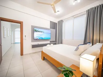 a bedroom with a bed and a flat screen tv at Plaza Achim 6b, Modern Apt 250m From Sosua Beach in Sosúa