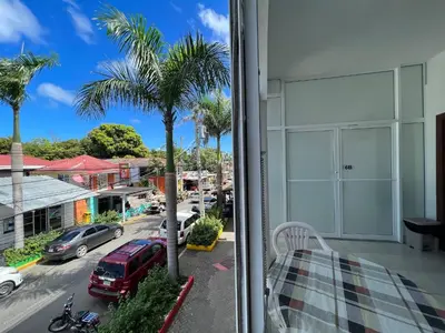 a balcony with a palm tree and a street at Plaza Achim 6b, Modern Apt 250m From Sosua Beach in Sosúa
