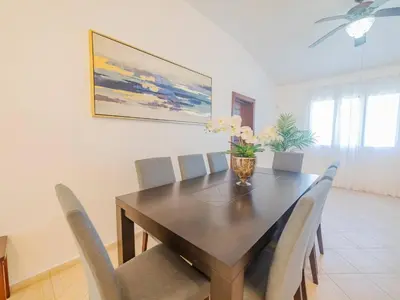 a dining room table with chairs and a vase with flowers on it at 7br Massive Villa In Sosa - 2mins From Nightlife in Sosúa