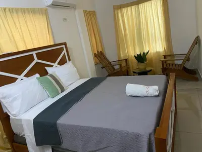a large bed in a bedroom with two chairs at Apartamento JGB 2 in Sosúa